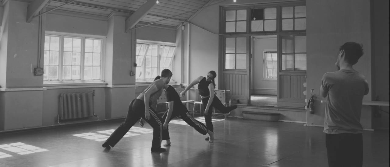 Open Rehearsal Jack Philp black and white image in a studio 3 dancers, Jack observing