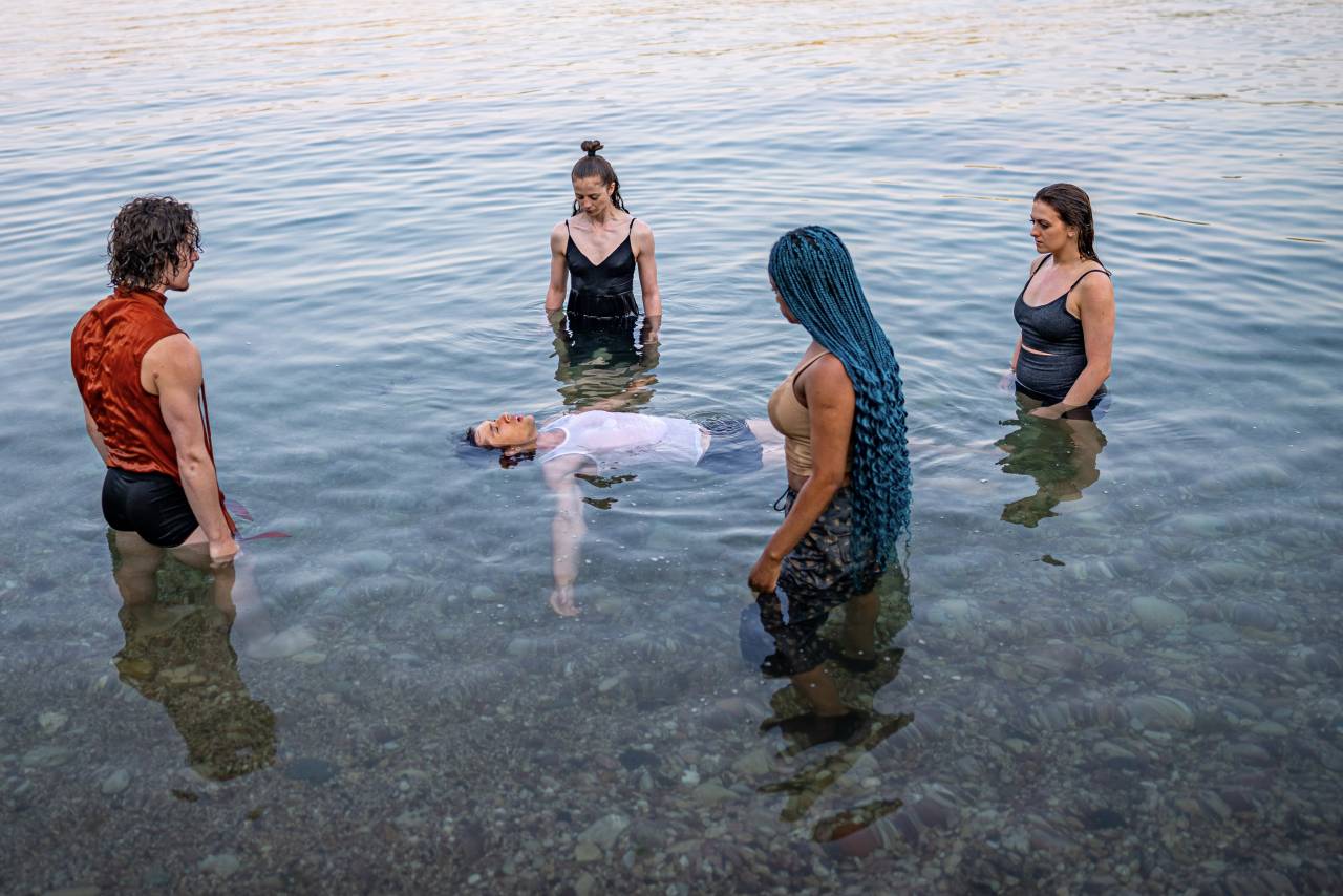 dancers surrounding one floating in the sea