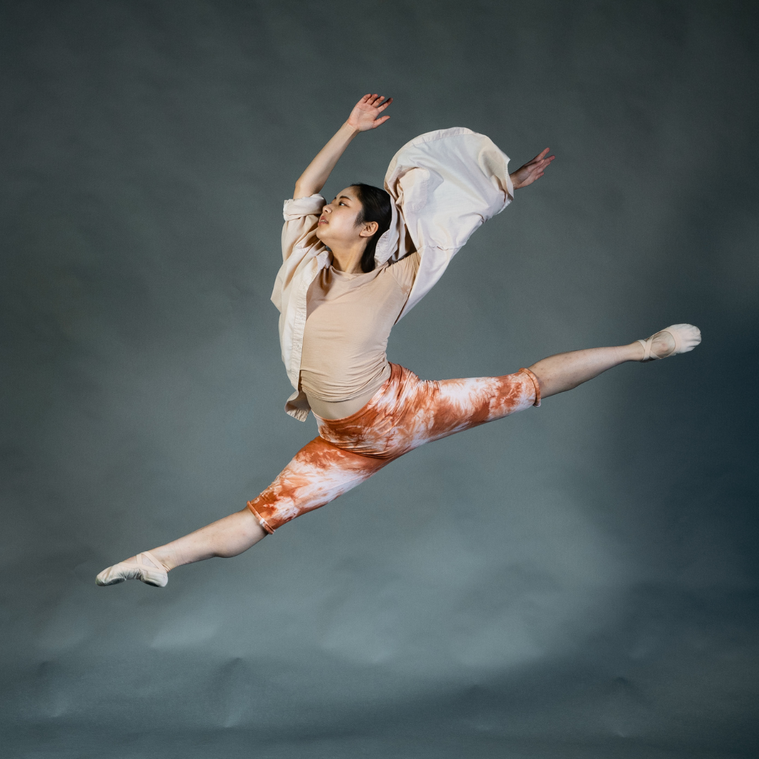 dancer in leaping splits and orange leggings