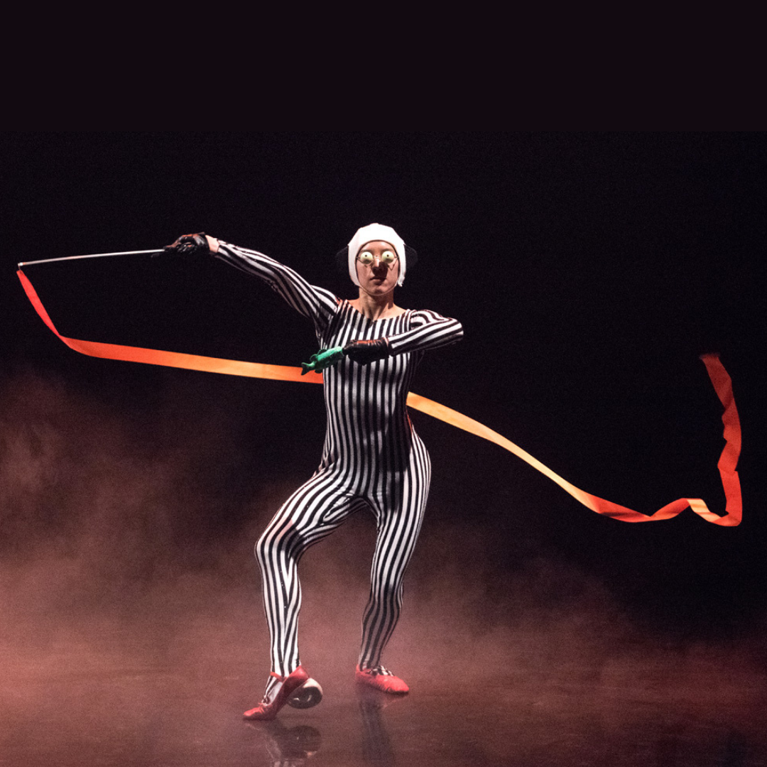 a performer in striped leotard and swimming cap waving a ribbon