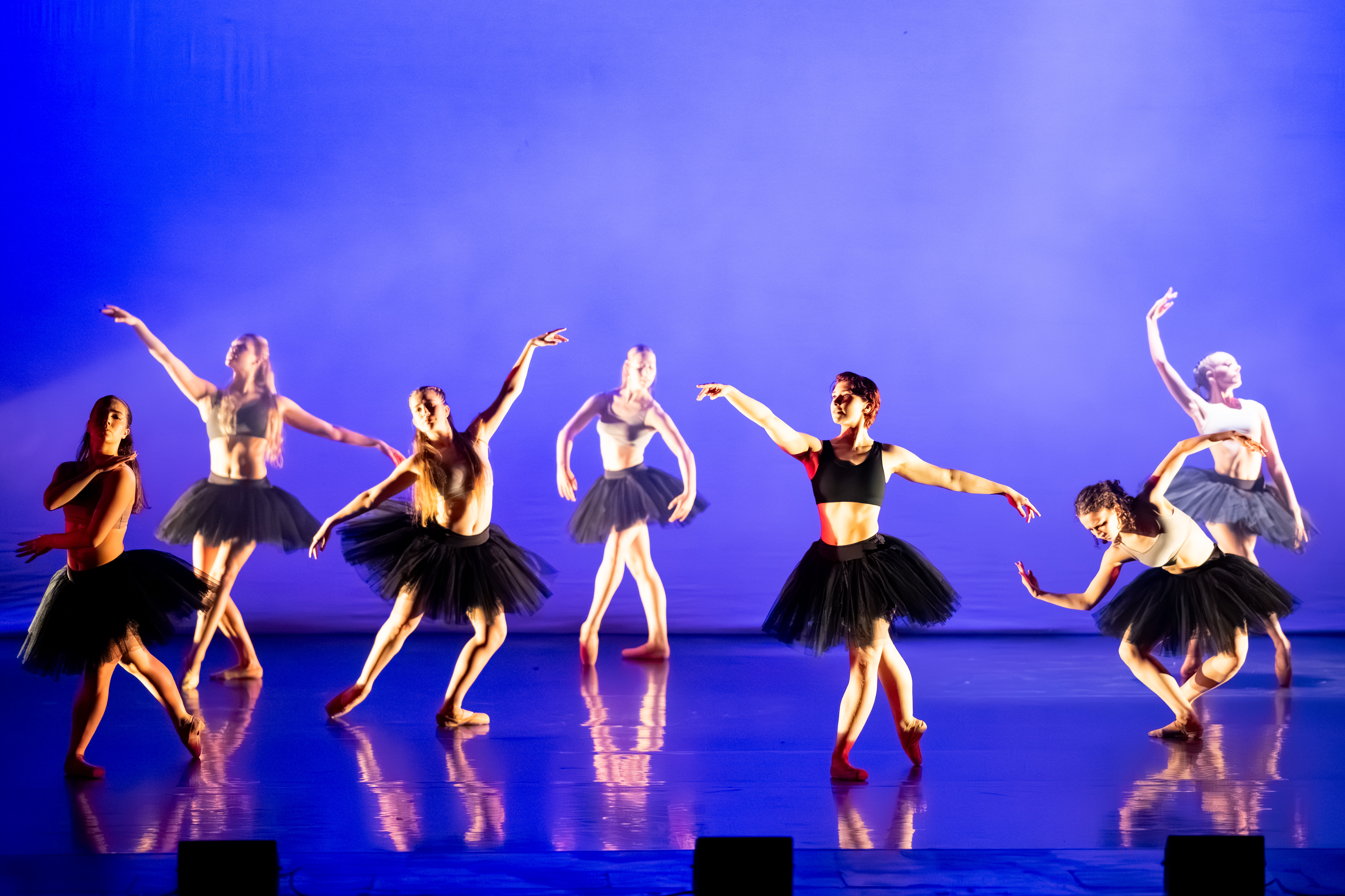 young ballet dancers in black on a blue stage