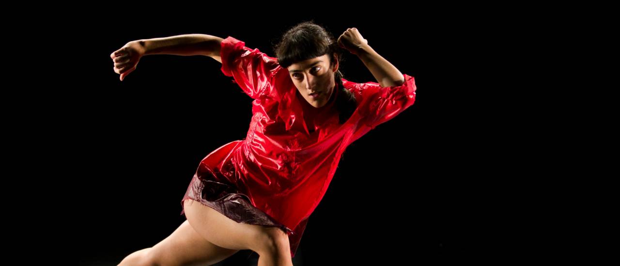 Girl in a red top appearing to be running to the right but looking over to her left