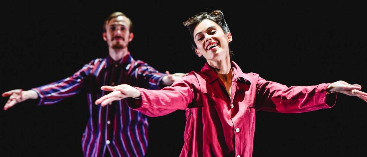 2 dancers wearing stripped pajamas, arms stretched out smiling at the audience