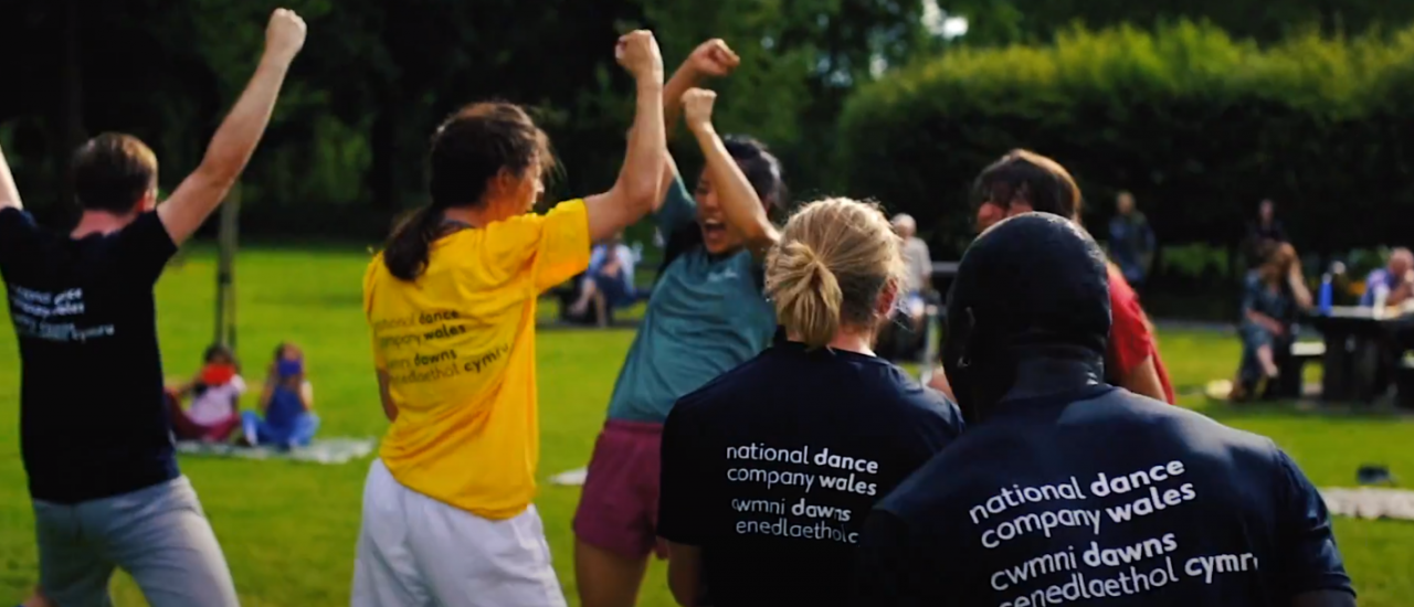 dancers in ndcwales tshirts dancing outside and cheering on a sunny day