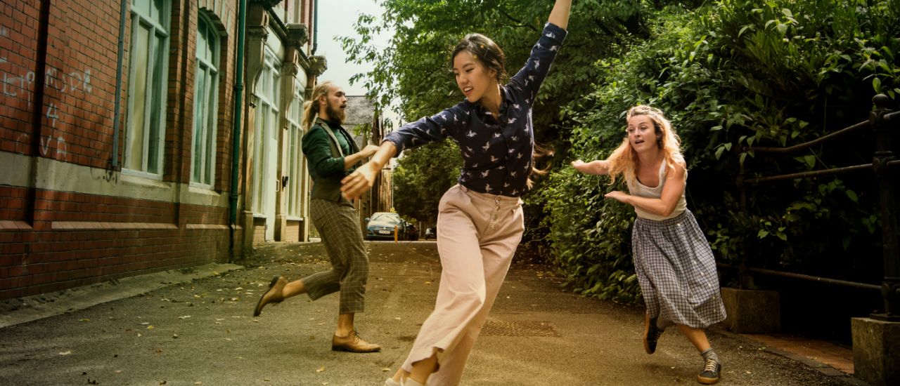 3 dancers outside smiling under blue skies 