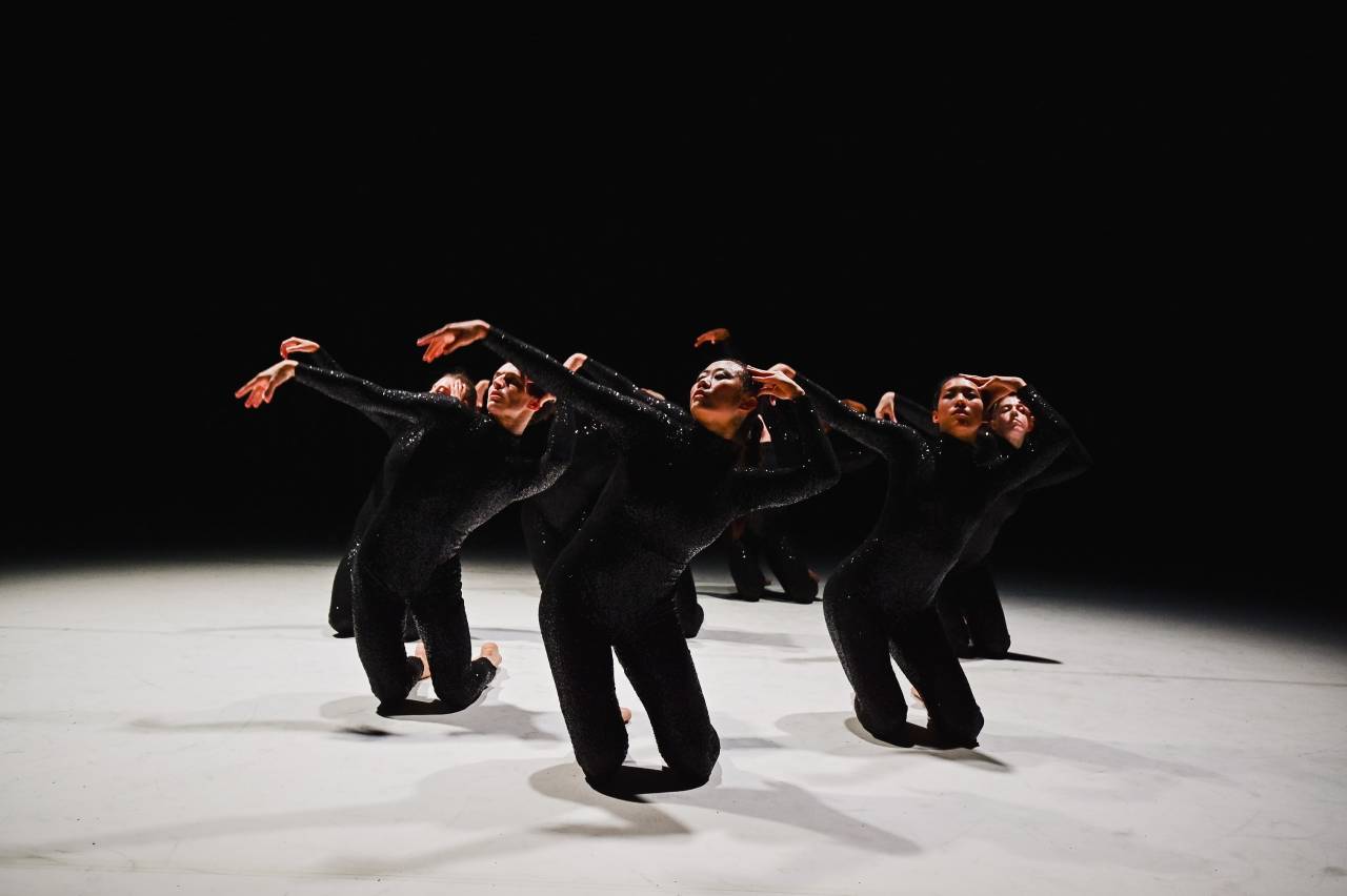 dancers kneeling with arms out and heads back