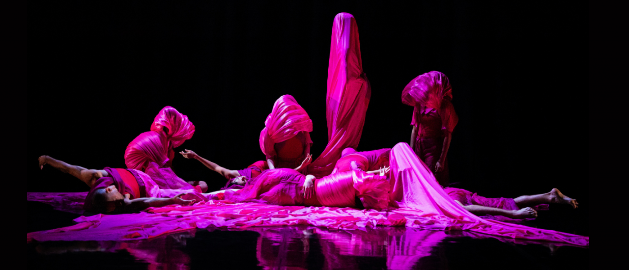 dancers under pink light wrapped in silky fabric