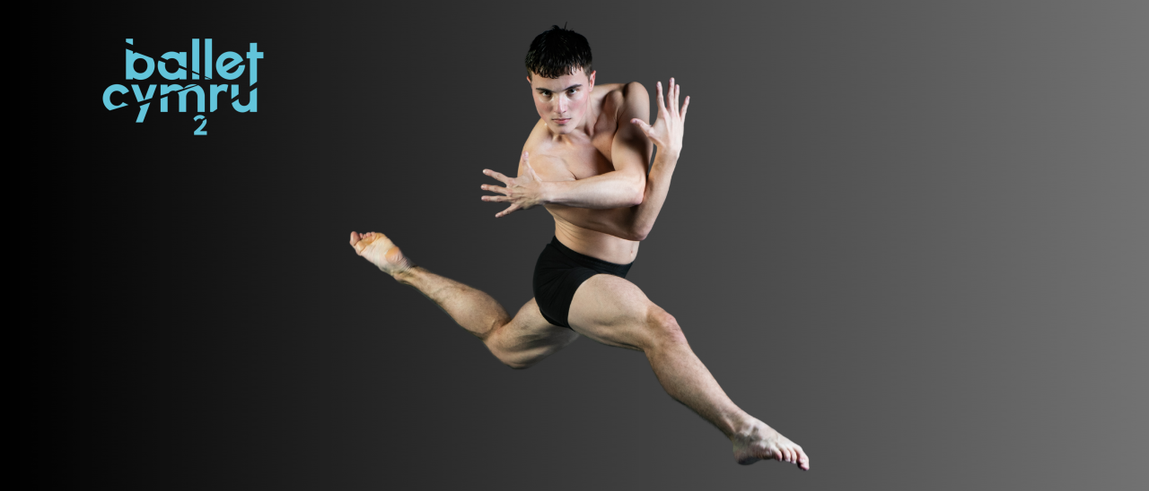 male presenting dancer in shorts leaping on grey background 
