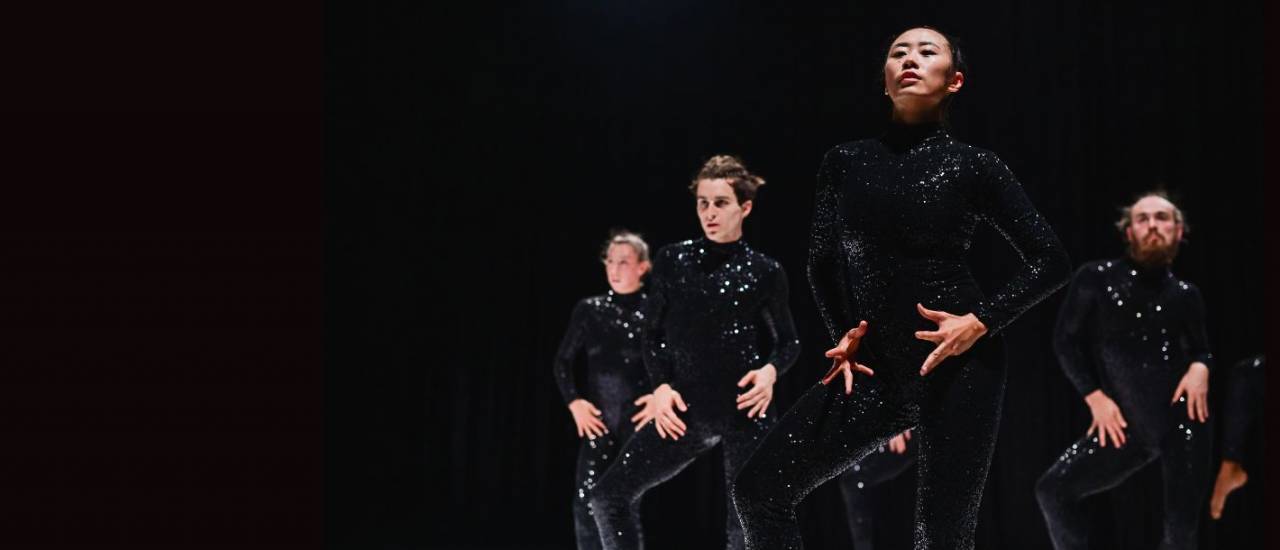 dancers in black sequin costumes moving together