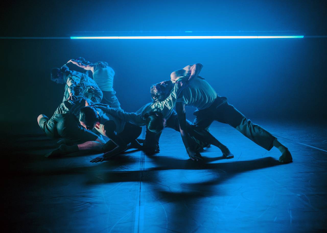 a group of dancers moving quickly under a blue light bar