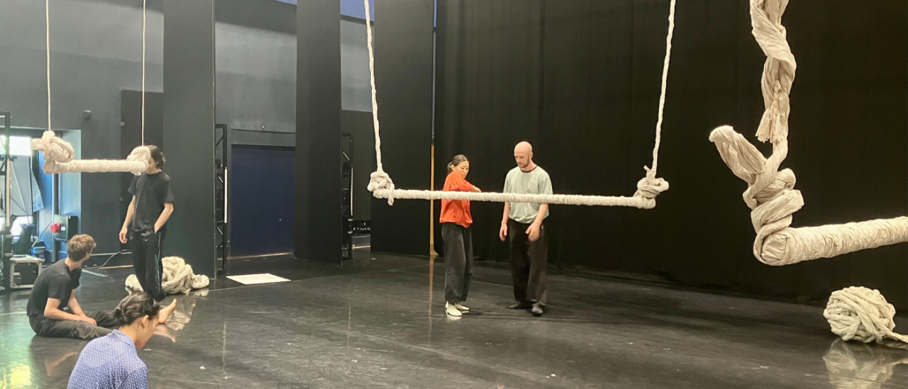 dancers in a space with a swing made of paper 