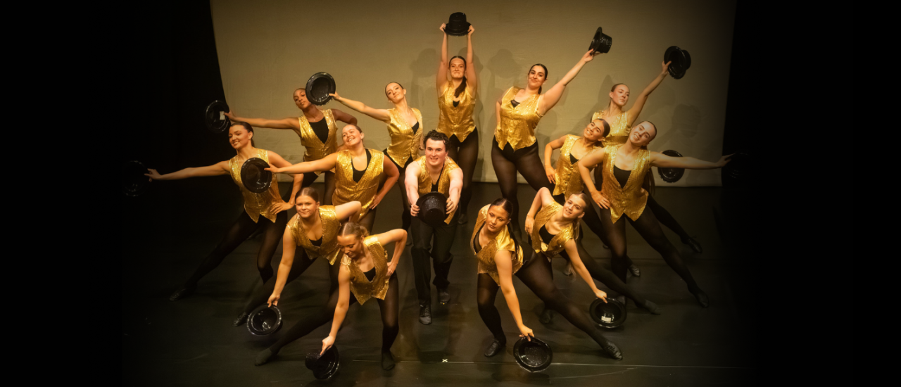 teenage dancers in gold waistcoats and top hats, holding them out, arms in a circle, its a fun jazzy photo